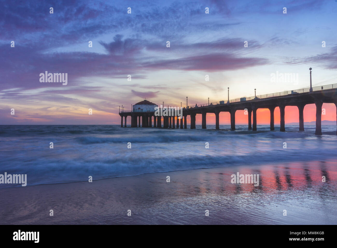 Lunga esposizione shot colorata del Cielo e nubi su Manhattan Beach Pier al tramonto con regolare lavaggio onde sulla spiaggia, Manhattan Beach, Californi Foto Stock