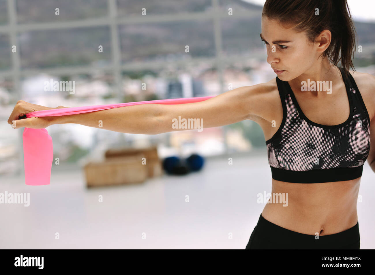 Attenti alla salute della donna che esercitano con banda di resistenza al fitness studio. Femmina in sportswear bracci facendo stretching allenamento con la banda di resistenza. Foto Stock