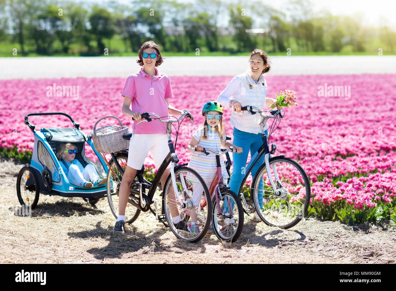 Felice famiglia olandese Bicicletta Equitazione in tulip campi di fiori in  Paesi Bassi. Madre e bambini su biciclette a fioritura di tulipani in Olanda.  Bambino in rimorchio bici Foto stock - Alamy