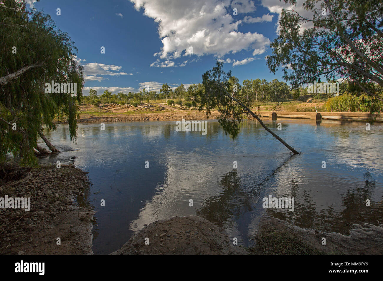Paesaggio con fiume di Bowen, con cielo blu e nuvole riflettono in acque calme, orlati con riva sabbiosa e alberi nativi in Western Australia Queensland Foto Stock