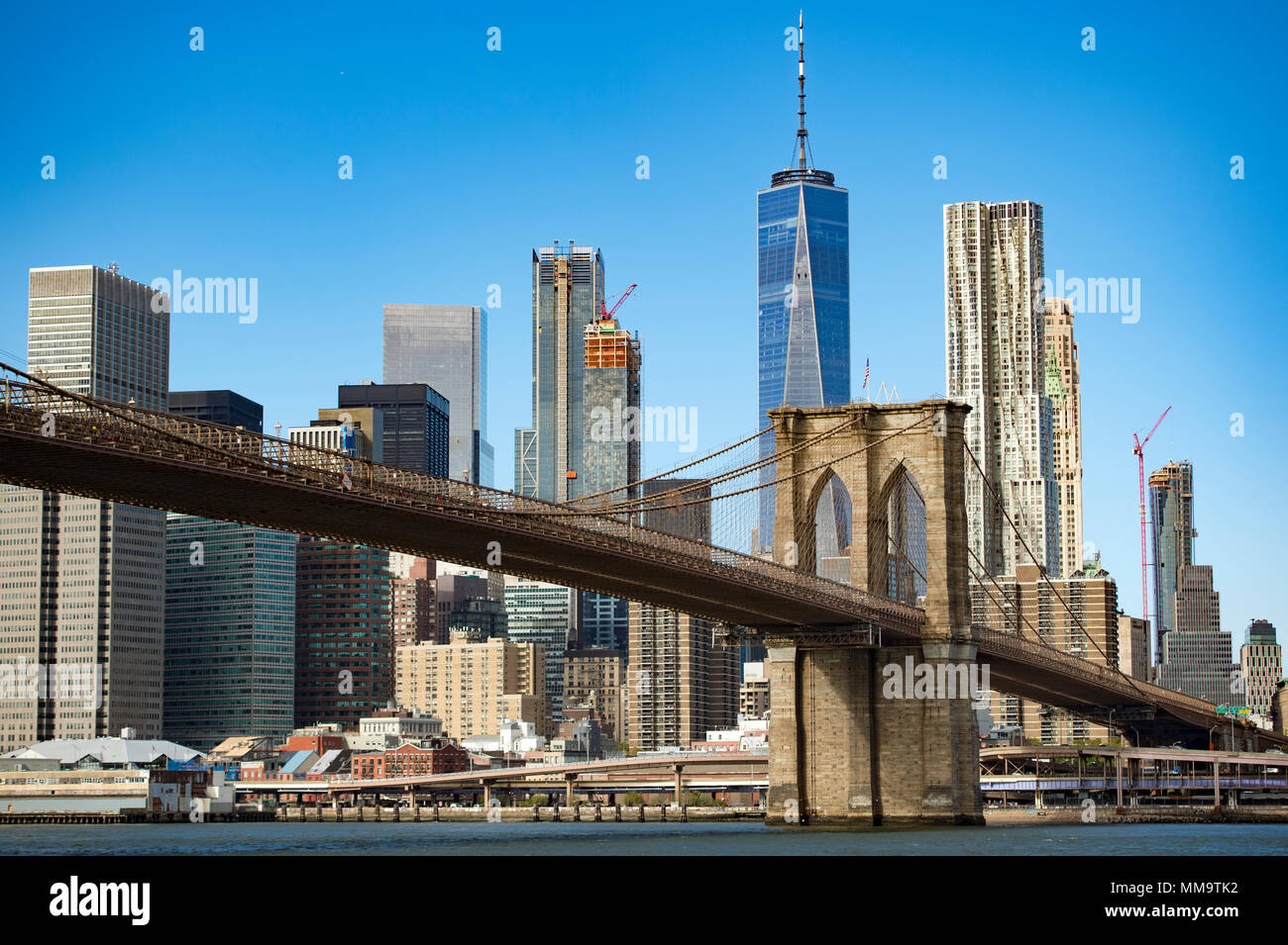 Skyline di Manhattan con il ponte di Brooklyn e la One World Trade Center in background durante una giornata di sole in New York, Stati Uniti d'America. Foto Stock