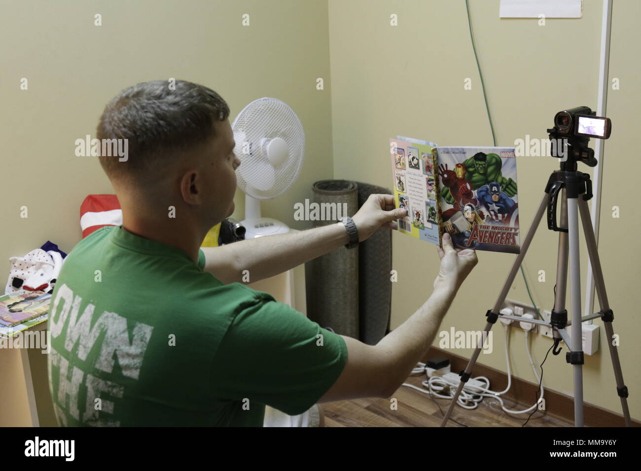 20170910-A-RW personale053-014 Sgt. Christopher Gilkison, paralegal NCOIC per la 371ª Brigata di supporto, mostra la pagina che sta leggendo a una telecamera per i suoi figli in uso nel Regno attraverso il programma di lettura su Camp Arifjan in Kuwait il 10 settembre 2017. (U.S. Esercito foto di Sgt. 1. Classe Charles Highland) Foto Stock