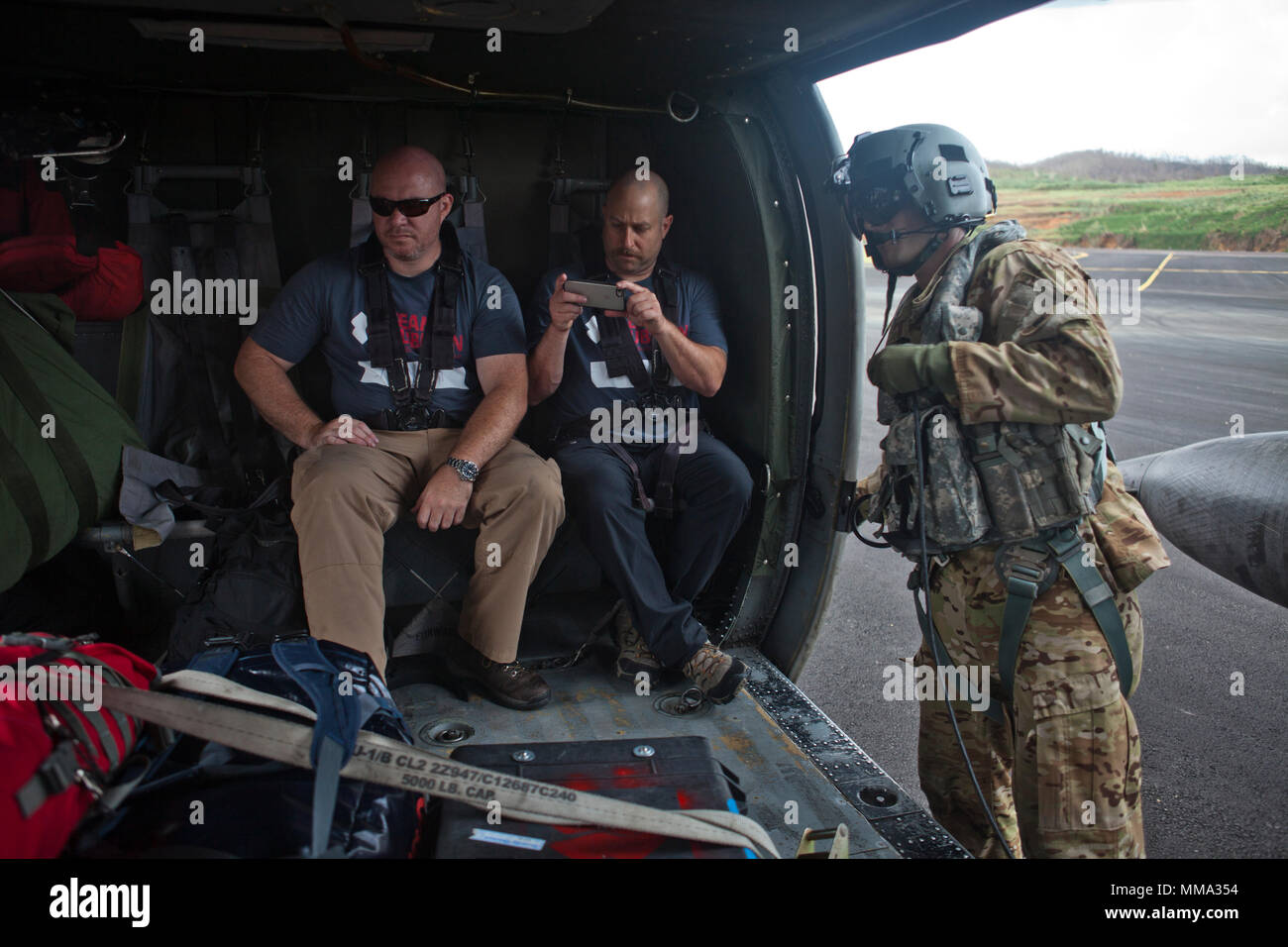Il personale di soccorso attendono il decollo in U.S. Esercito UH-60 Black Hawk elicottero con Joint Task Force - Isole Sottovento a Douglas-Charles Aeroporto di Melville Hall, Dominica, Sett. 27, 2017. Su richiesta degli Stati Uniti Agenzia per lo Sviluppo Internazionale, JTF-li ha distribuito degli aerei e i membri del servizio per assistere nella consegna di aiuti umanitari e di soccorso in caso di catastrofe le forniture a Dominica. La task force è un militare statunitense di unità composta di Marines, soldati, marinai e aviatori, e rappresenta U.S. Comando Sud la risposta primaria per gli uragani che hanno colpito la zona. (U.S. Marine Corps p Foto Stock
