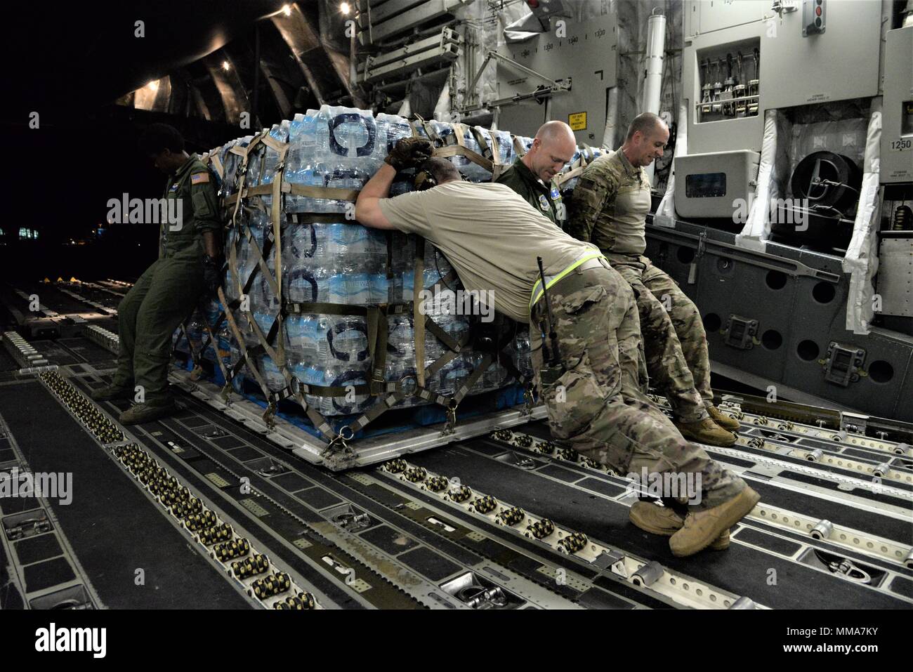 Il 3d Airlift Squadron raggiunge 7170 equipaggio e 123risposta di emergenza gruppo aviatori lo scarico di acqua e di cibo da una C-17 Globemaster III per essere distribuiti ai superstiti di uragano a San Juan Luis Muñoz Marín Aeroporto di San Juan, Puerto Rico, a sett. 30, 2017. Raggiungere 7170 consegnato 118 mila libbre di pasti pronti da mangiare e acqua in bottiglia per essere distribuito in tutta l'devastato Puerto Rico con l aiuto di aviatori da 123contingenza Gruppo di risposta. (U.S. Air Force foto di Tech. Sgt. Matt Davis) Foto Stock