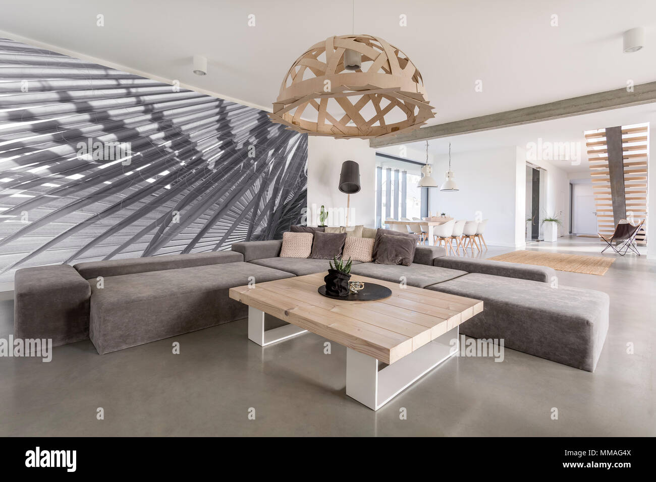 Camera con ampio divano, tavolo in legno e carta da parati foto Foto Stock