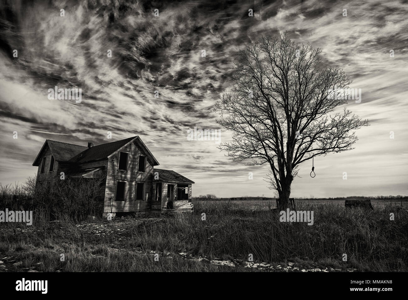 Foto in bianco e nero di un vecchio scary fattoria abbandonata che sta peggiorando con il tempo e l'incuria. Foto Stock