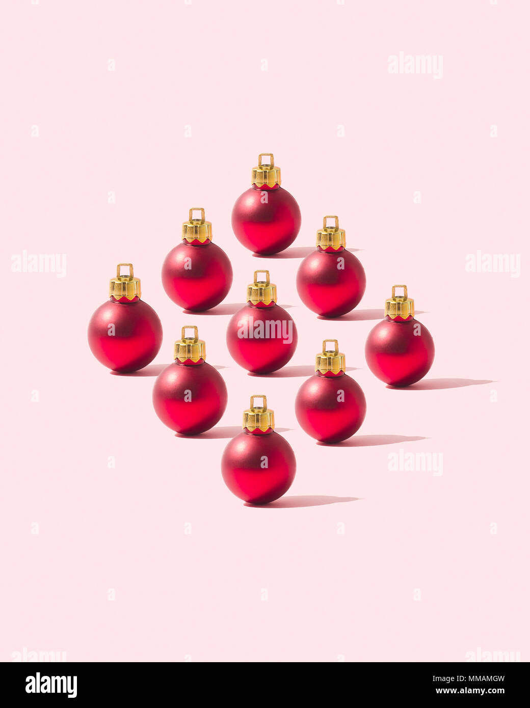 Rosso baubles di Natale organizzato in una forma a rombo su sfondo rosa Foto Stock
