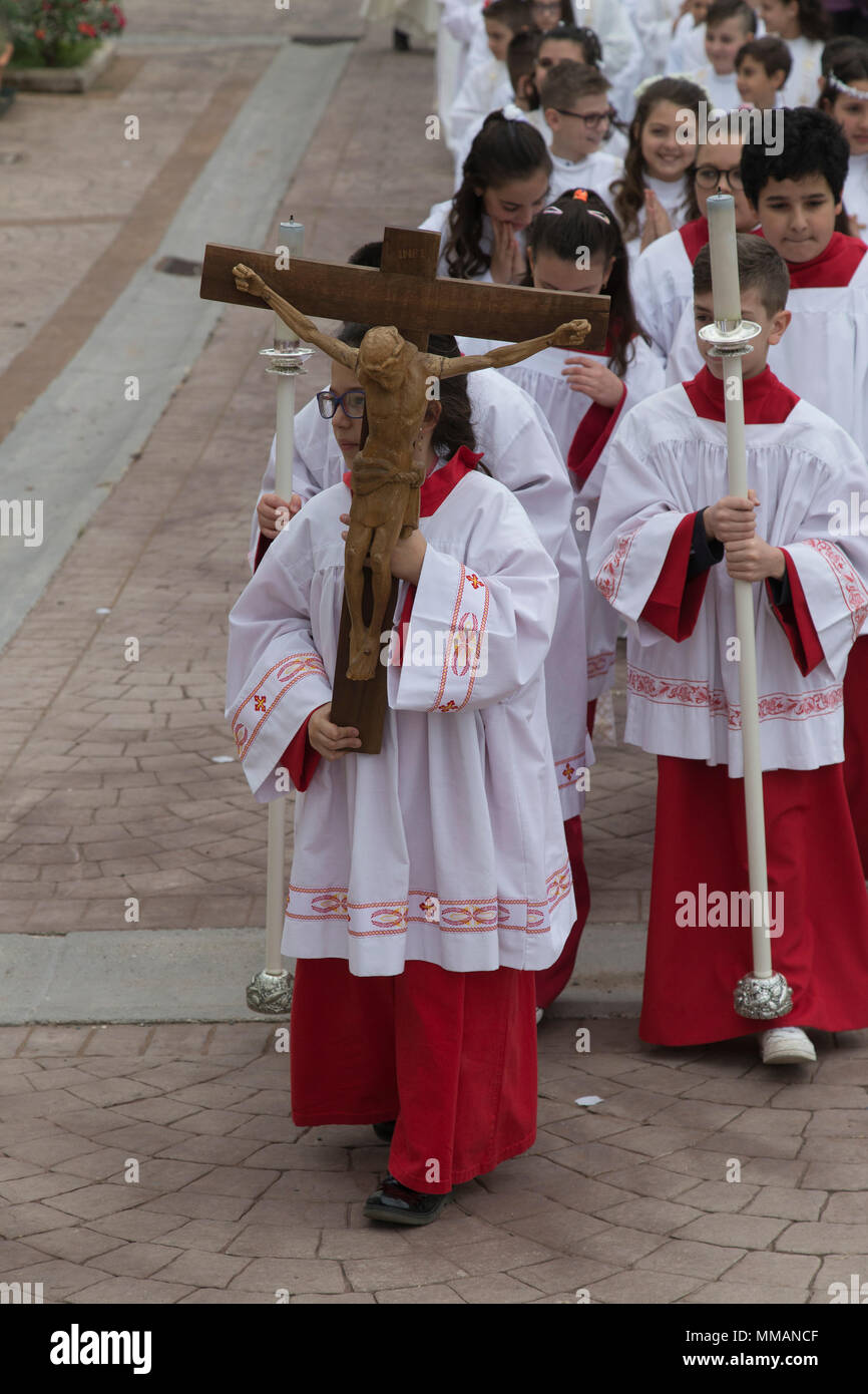 Sacerdote conduce la processione dei bambini circa per avere la loro prima Comunione in Bracciano Italia Foto Stock