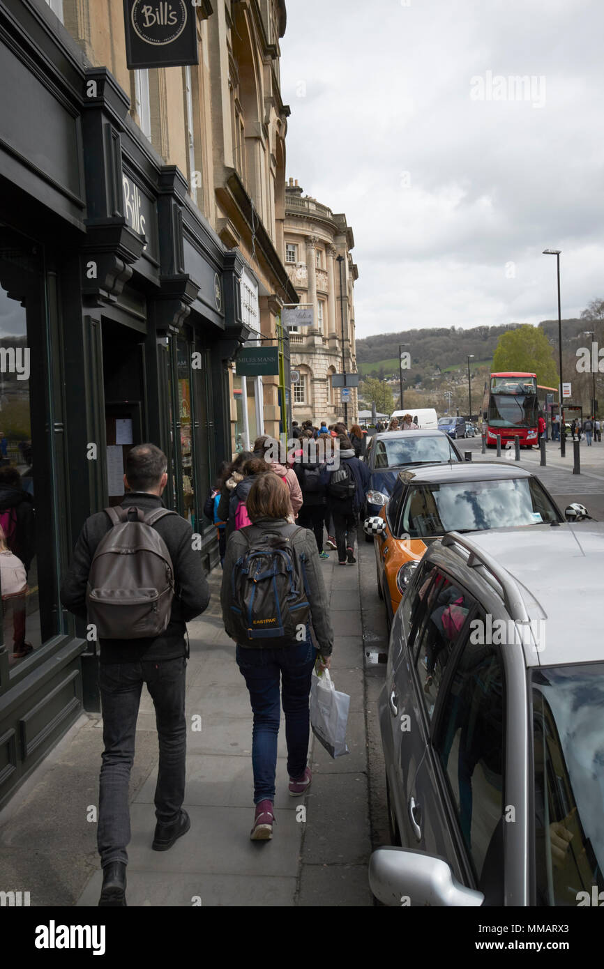 Gruppo di scolari in visita a piedi lungo pranzo marciapiede nel centro della città di Bath England Regno Unito Foto Stock