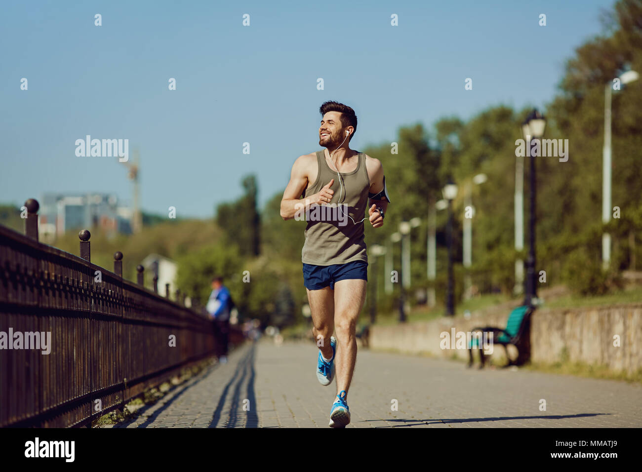 Un maschio di runner corre lungo la strada che porta al parco. Foto Stock