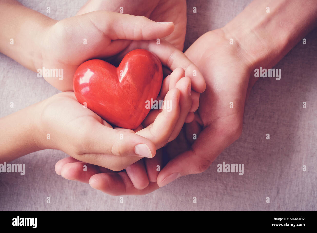 Adulto e bambino mani holiding cuore rosso, la cura della salute, amore, donazione, assicurazione e il concetto di famiglia Foto Stock