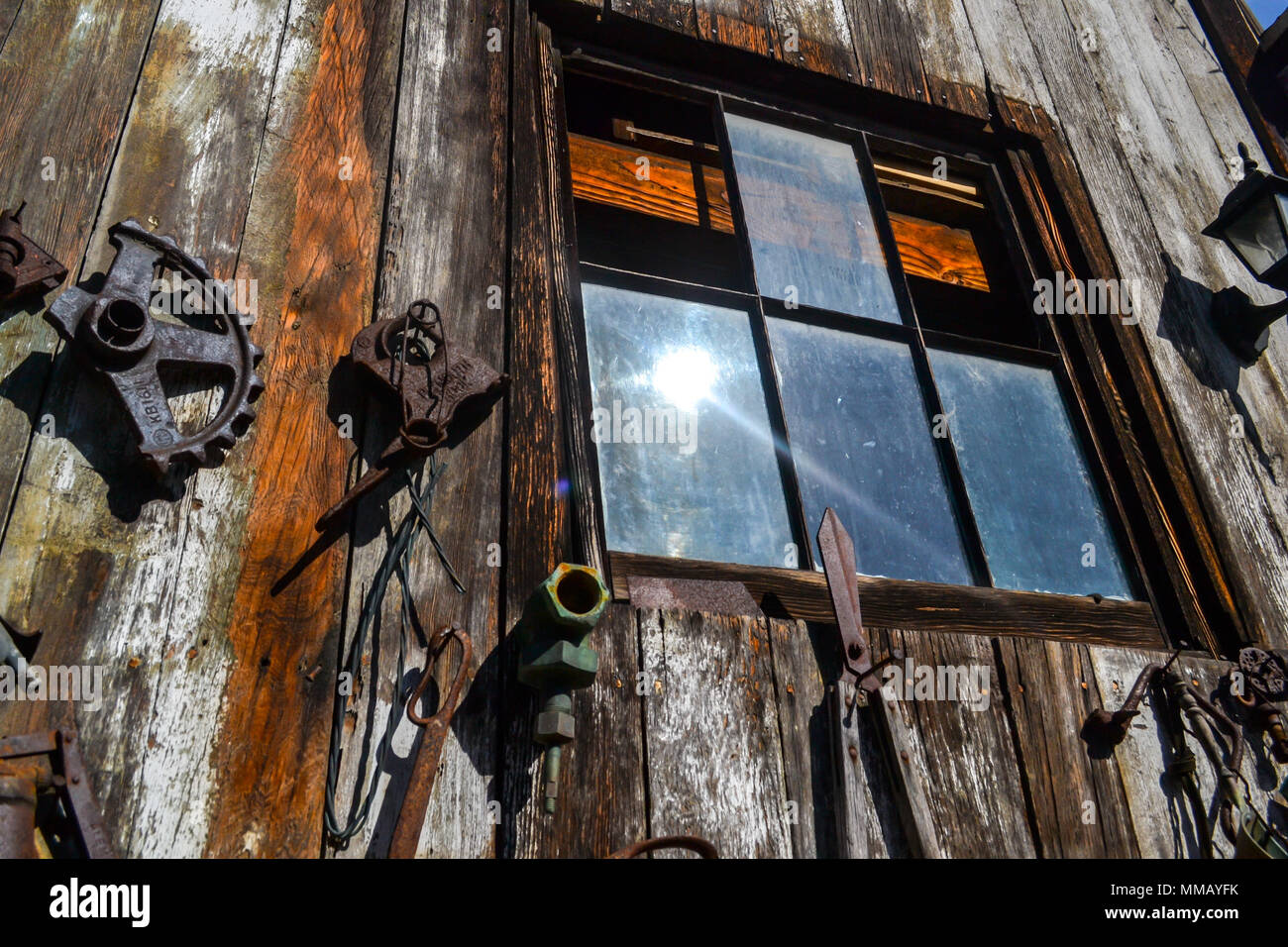 Rancho Bernardo in California - la più antica cantina di lavoro. Vintage scene arrugginita farm equipment per mulini a vento pigramente di filatura nella brezza. Fiori Foto Stock