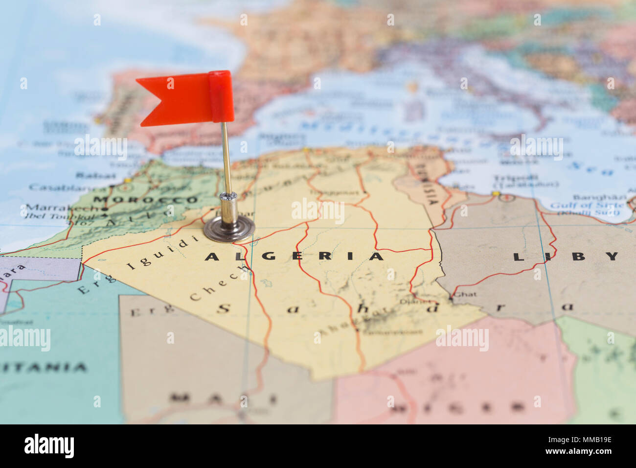 Piccola bandiera rossa segna il paese africano di Algeria su una mappa del mondo. Foto Stock