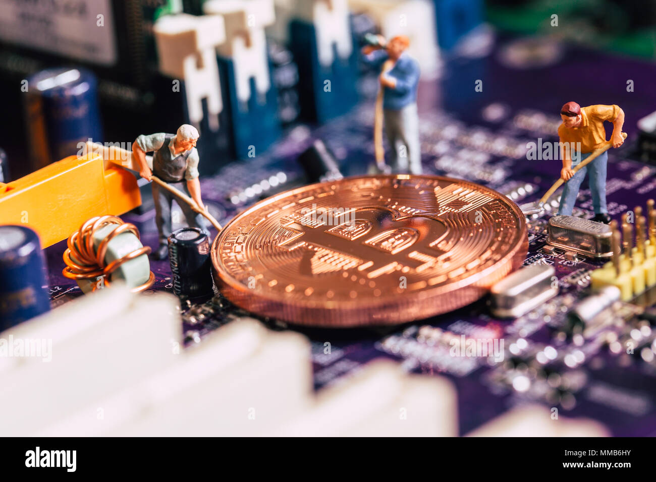 Lavoratore in miniatura scavare oro minatore bitcoin sulla scheda di circuito elettronico Foto Stock