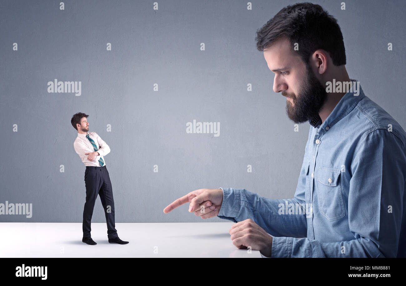 Giovane imprenditore professionale essendo arrabbiato con un altro imprenditore in miniatura Foto Stock