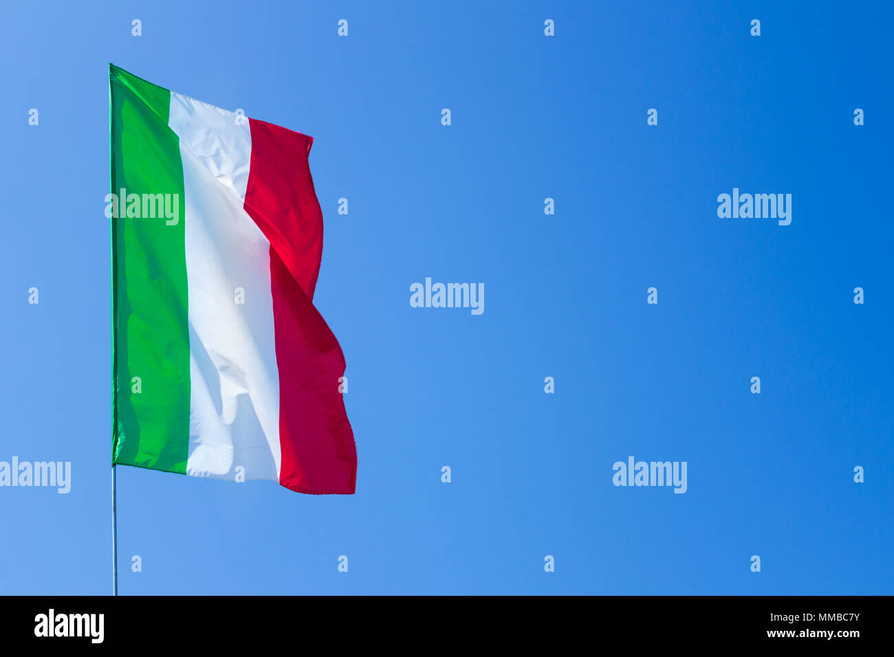 Sventola bandiera italiana contro il cielo blu Foto Stock