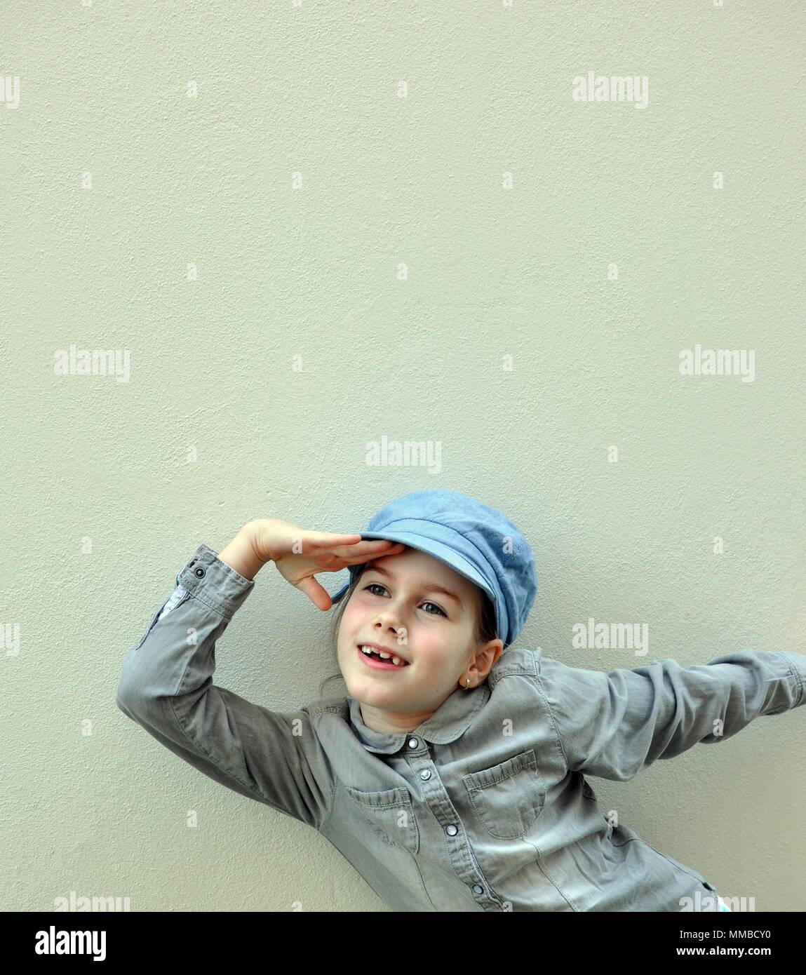 Bambino, ragazza, 8 anni, sorridente e giocando con le mani, guardando in lontananza, vista anteriore verticale, spazio di copia Foto Stock