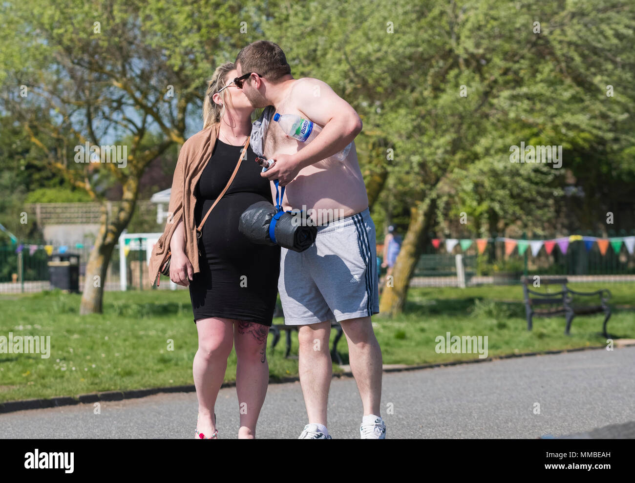 Una giovane coppia baciare in un parco in un giorno caldo nel Regno Unito. Visualizzazione pubblica di affetto. PDA. Foto Stock