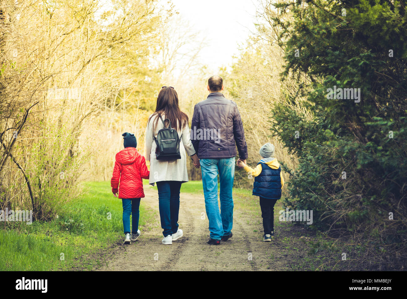 Felice giovane famiglia di trascorrere del tempo insieme al di fuori in natura. i genitori tiene le mani di bambini piccoli. Foto Stock