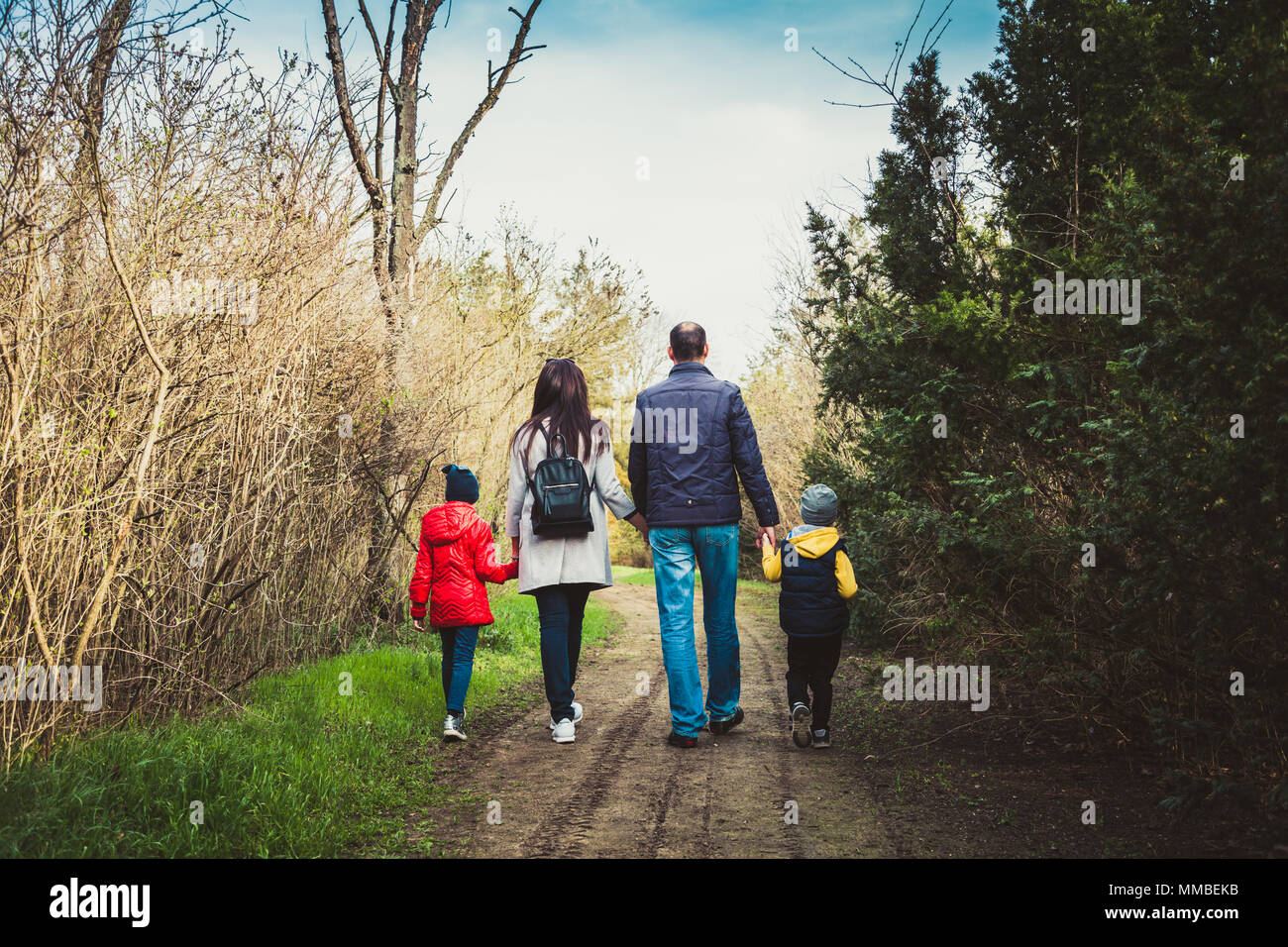 Felice giovane famiglia di trascorrere del tempo insieme al di fuori in natura. i genitori tiene le mani di bambini piccoli. Foto Stock