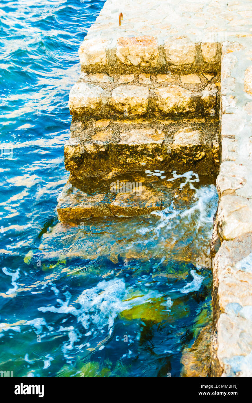 Il molo privato scale sul mare ondeggiante con acqua salata la frantumazione delle rocce. Foto Stock