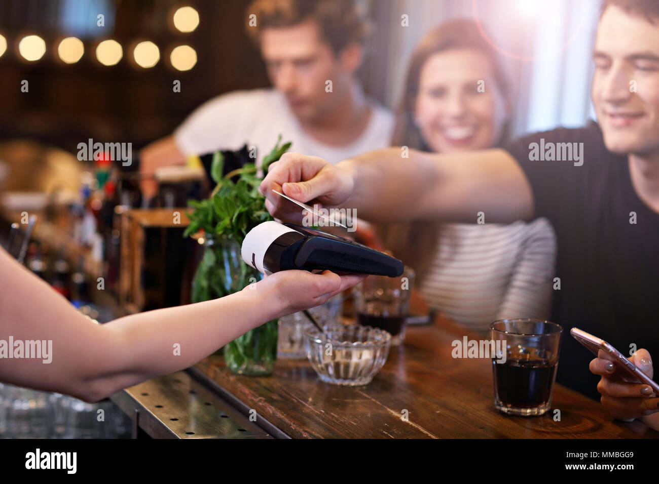 Gruppo di amici di pagare per il pasto in ristorante Foto Stock