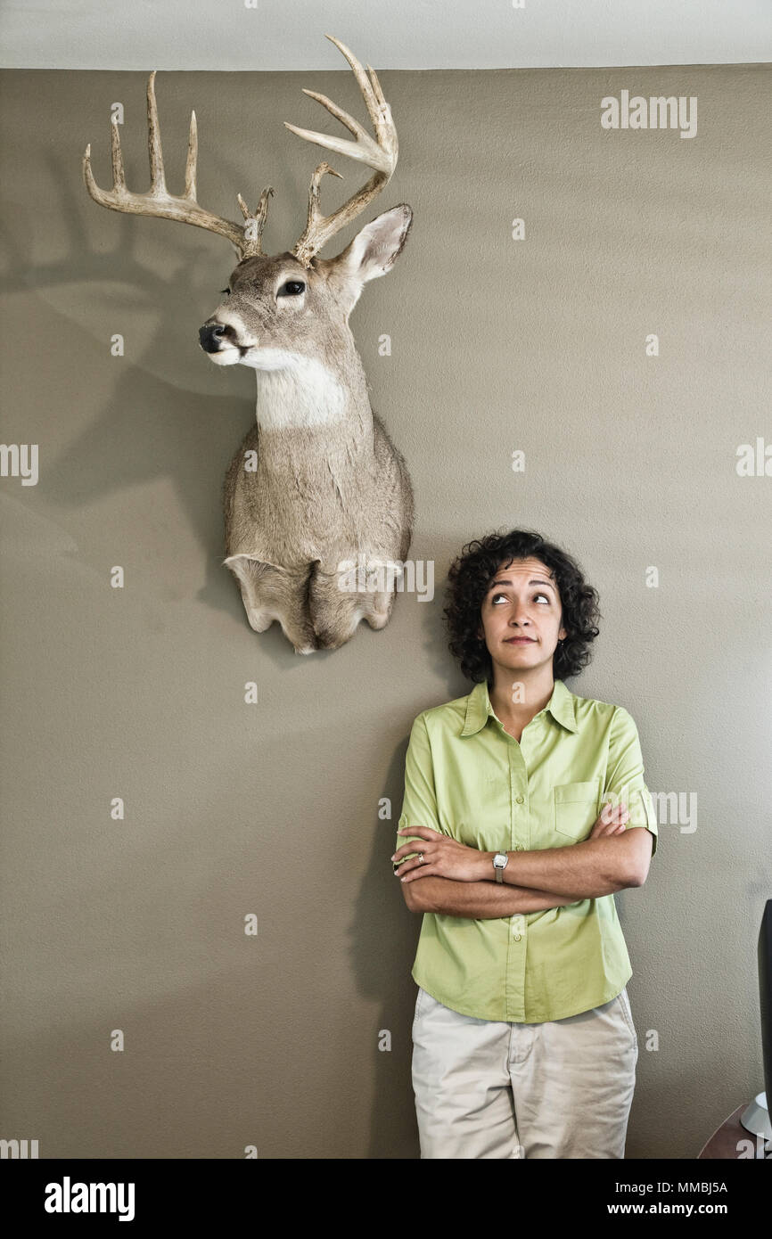 La donna in un ufficio con montata la testa di cervo. Foto Stock