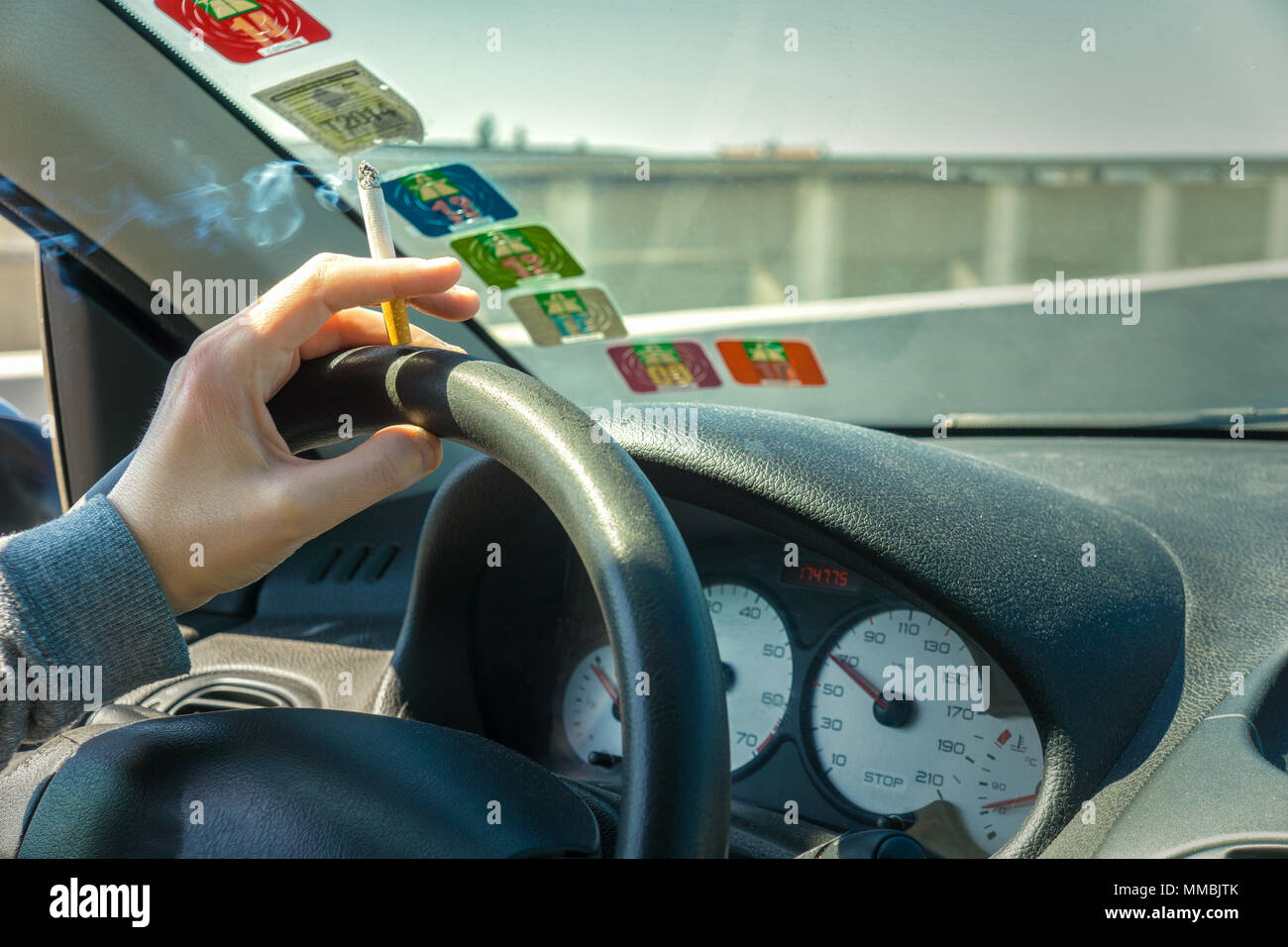 Il fumo durante la guida di un'auto in autostrada vista interna e spazio copia, Francia. Foto Stock