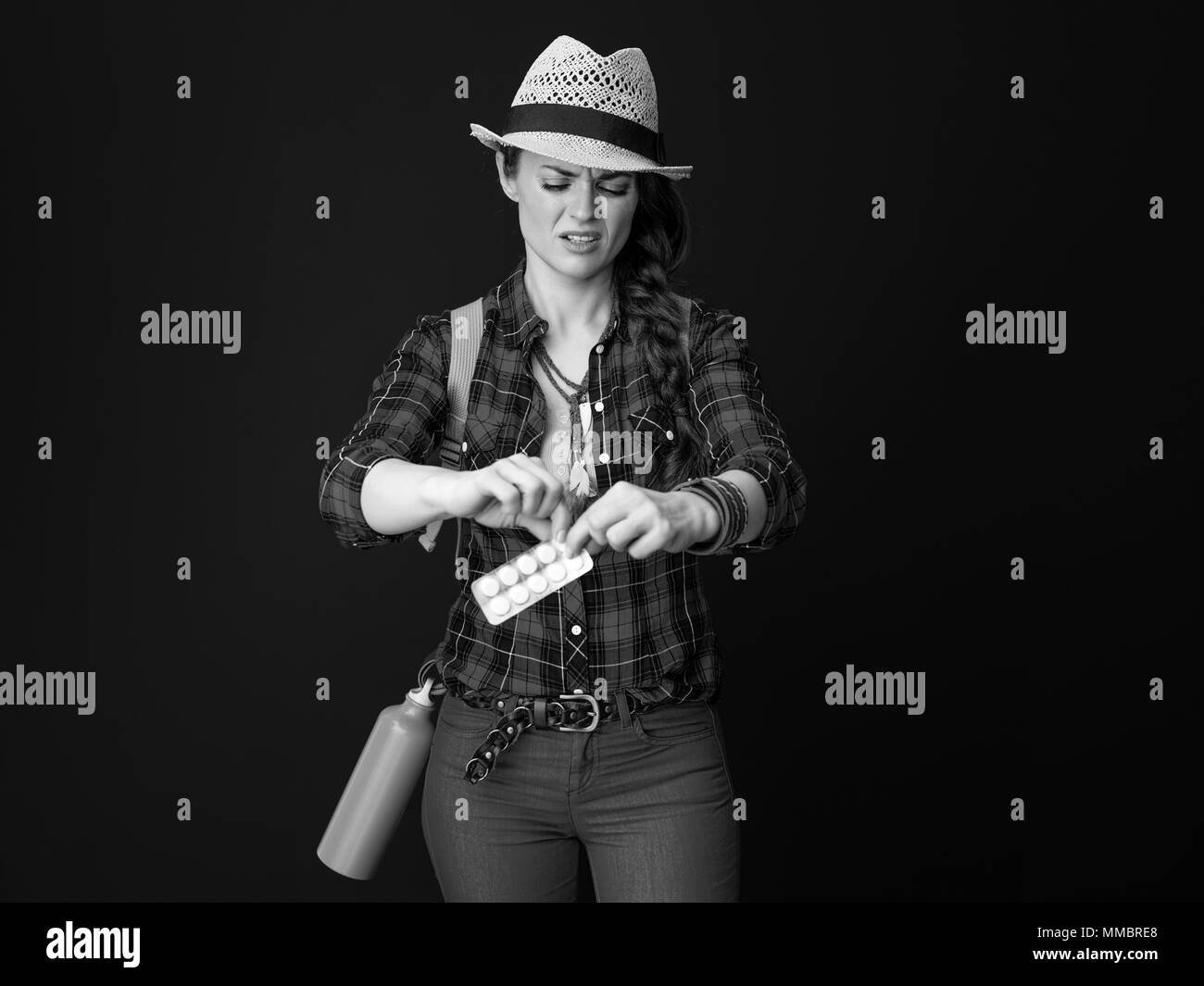 La ricerca di luoghi ispiratrice. giovani malati donna turistica in un plaid shirt prende una compressa al di fuori della confezione isolato su Foto Stock