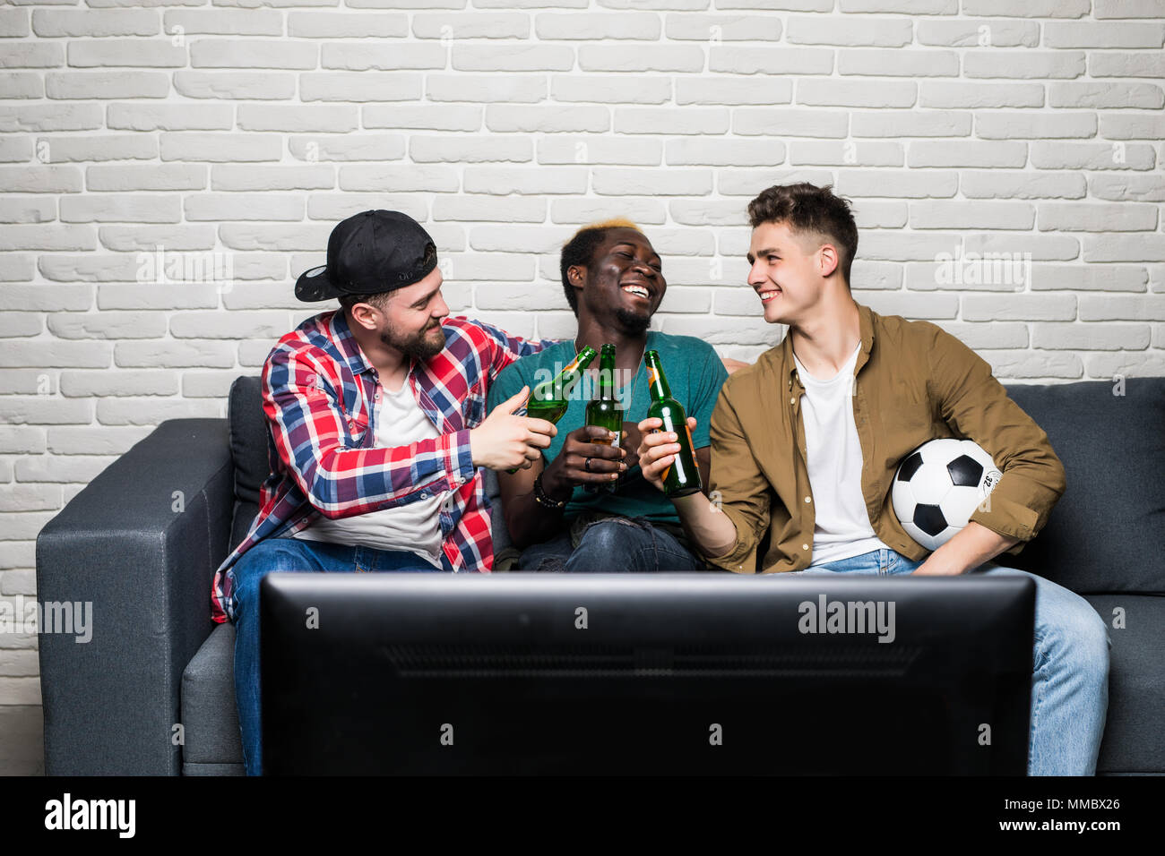 Foto di felice allegro uomini che tengono un bicchiere di birra e guardare la tv Foto Stock