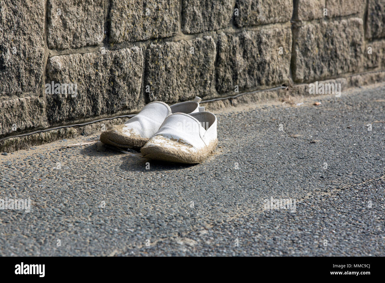 Una coppia di dimenticati, perse o abbandonate holiday beach scarpe, coperte in spiaggia di sabbia da un muro e da un parcheggio auto, Yaverland, Sandown, isola di Wight in Inghilterra. Foto Stock