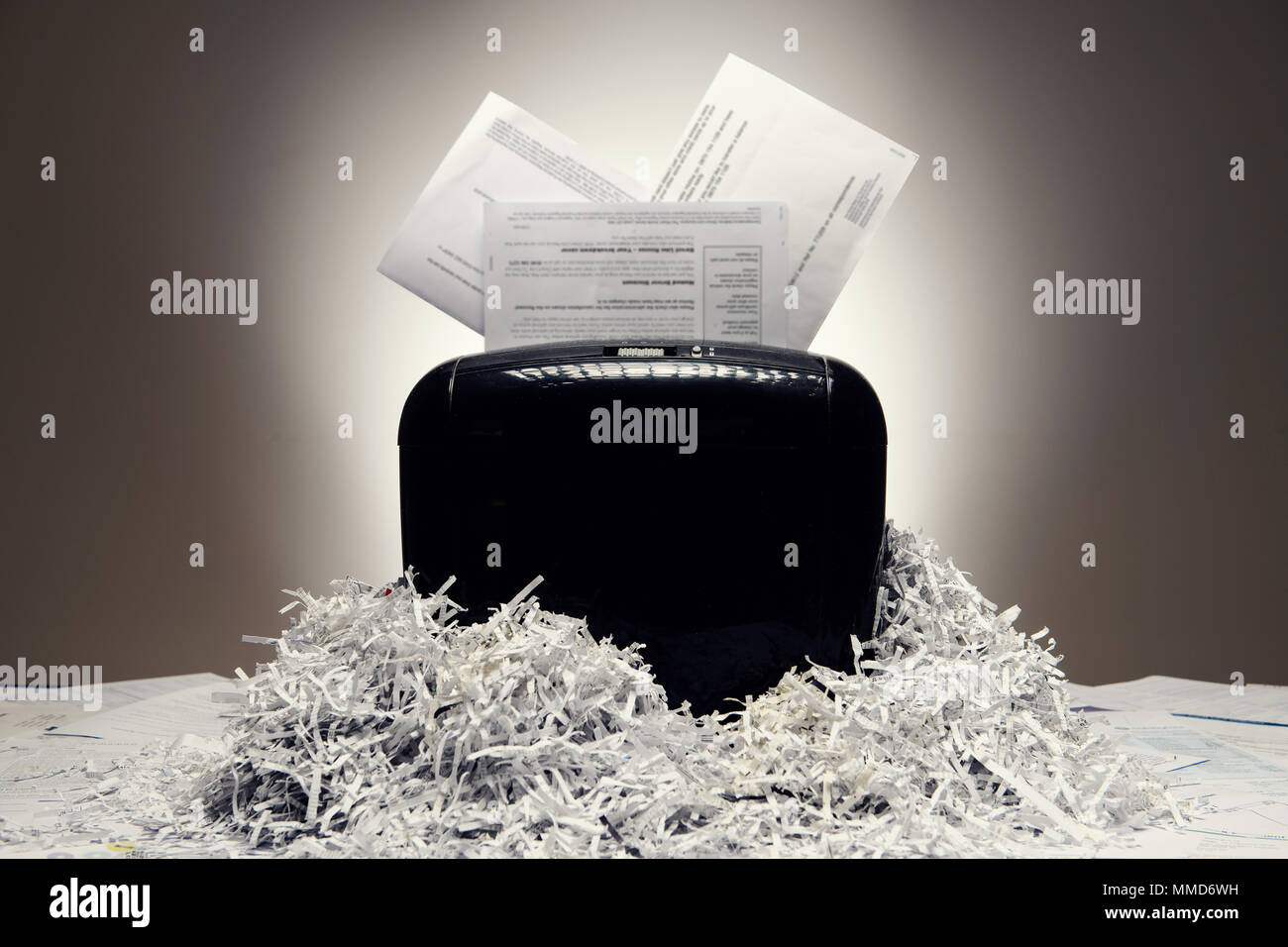 Office shredder e documenti personali essendo sminuzzato, con pile di carta tagliuzzata. Foto Stock