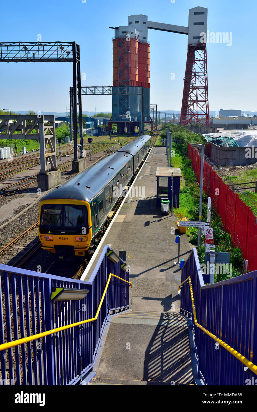 Avonmouth passeggero stazione ferroviaria con treni, in bulk di sfondo carbone silos di gestione. Avonmouth docks, Bristol, Regno Unito Foto Stock