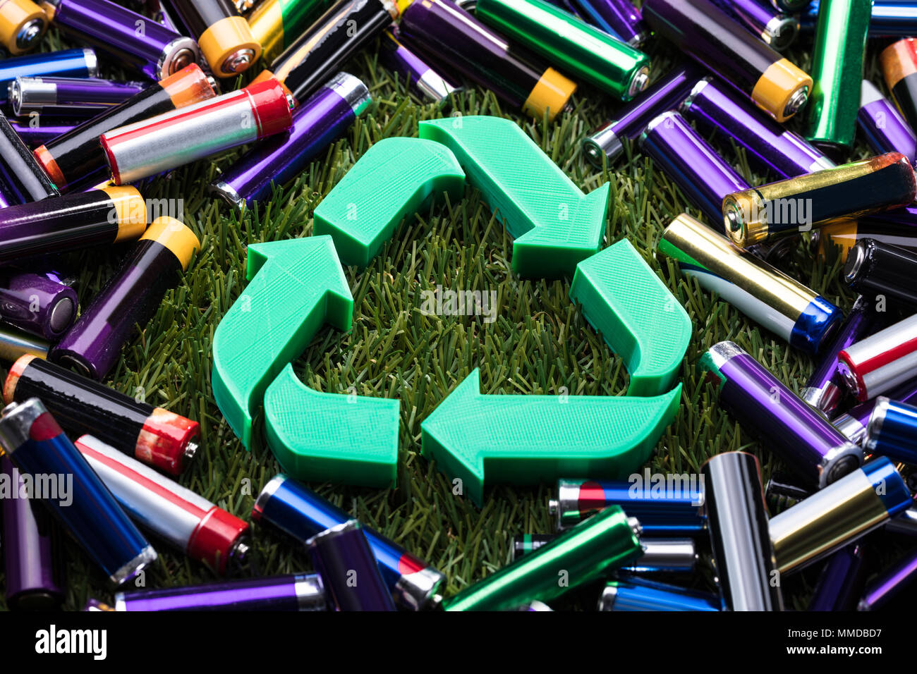 Vista in elevazione del verde Simbolo di riciclo circondato con batterie Foto Stock