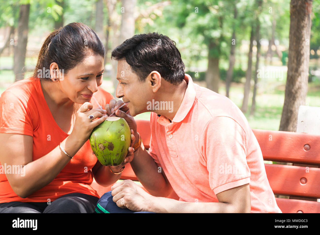 Due giovane fresca potabile Acqua di cocco seduto sulla spiaggia At-Park Foto Stock