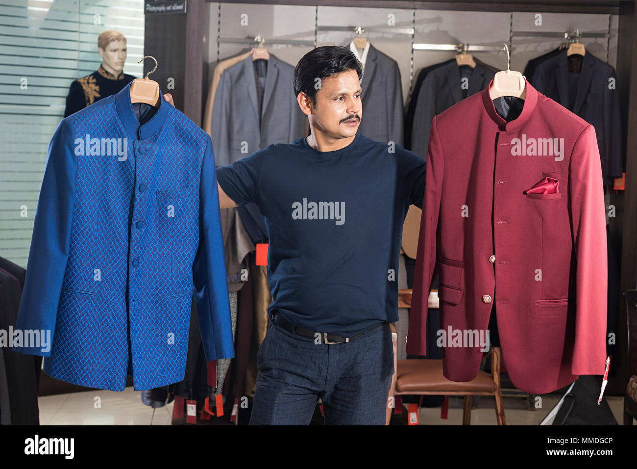 Un Venditore che vendono vestiti che mostra la scelta di rivestimento negozio dipartimentale Foto Stock
