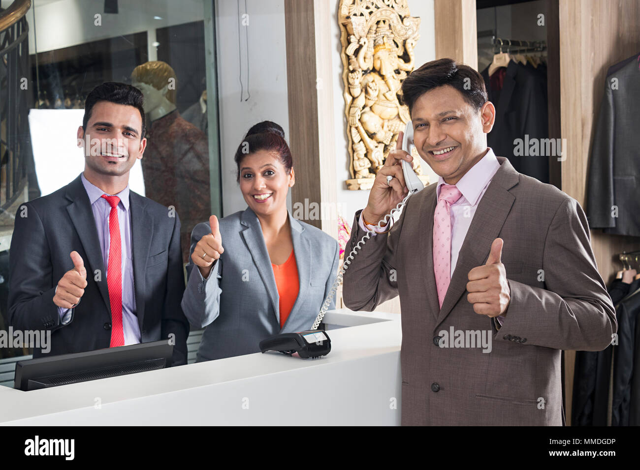 Due receptionist e imprenditore Hotel Prenotazione e parlare per telefono pollice in su Foto Stock