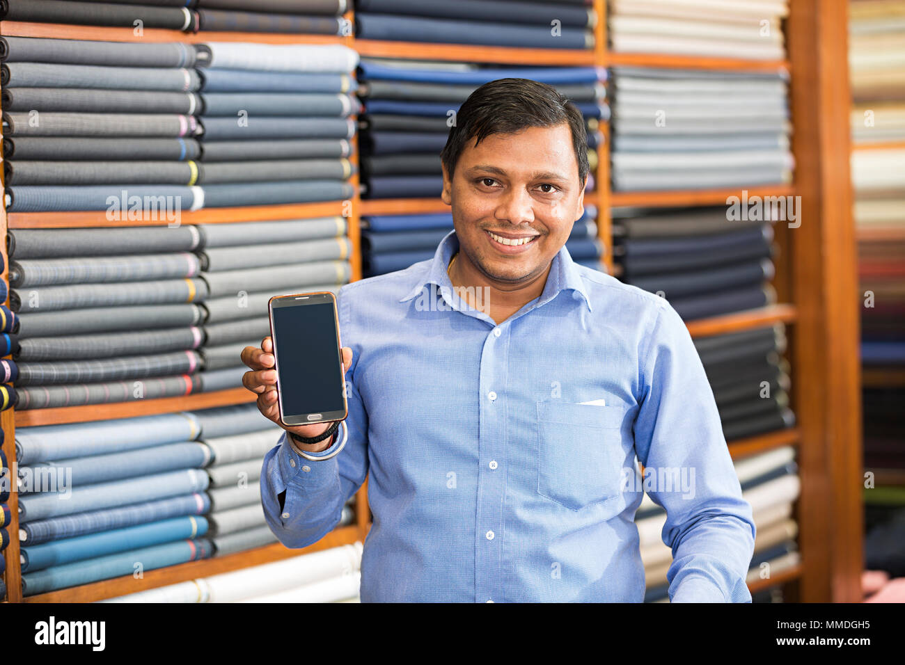 Un negoziante uomo Seeling mostra schermo di cellulare negozio di abbigliamento Foto Stock