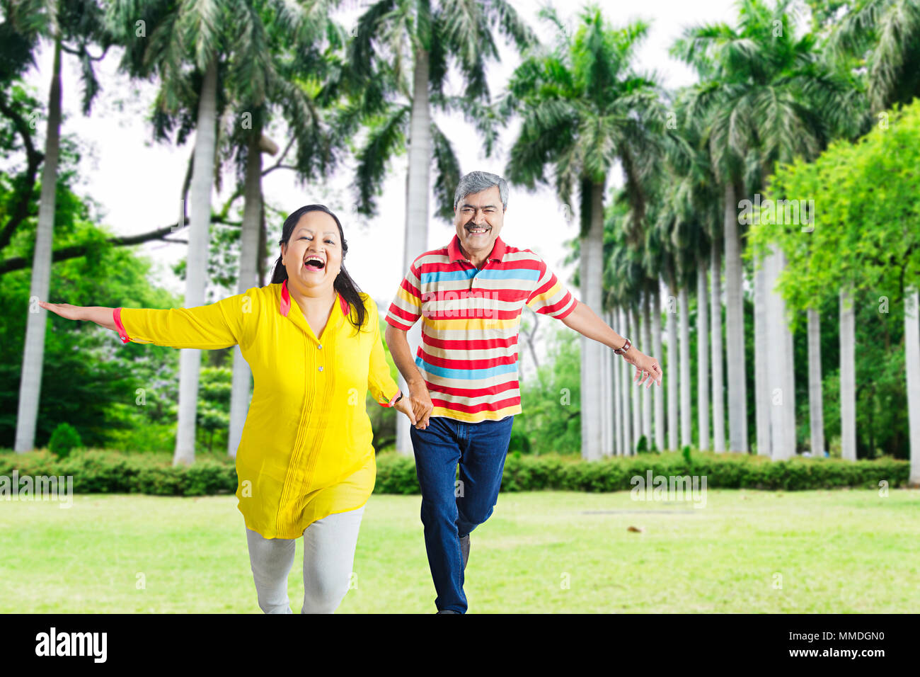 Due coppia Senior correndo insieme divertimento allegro in giardino Foto Stock