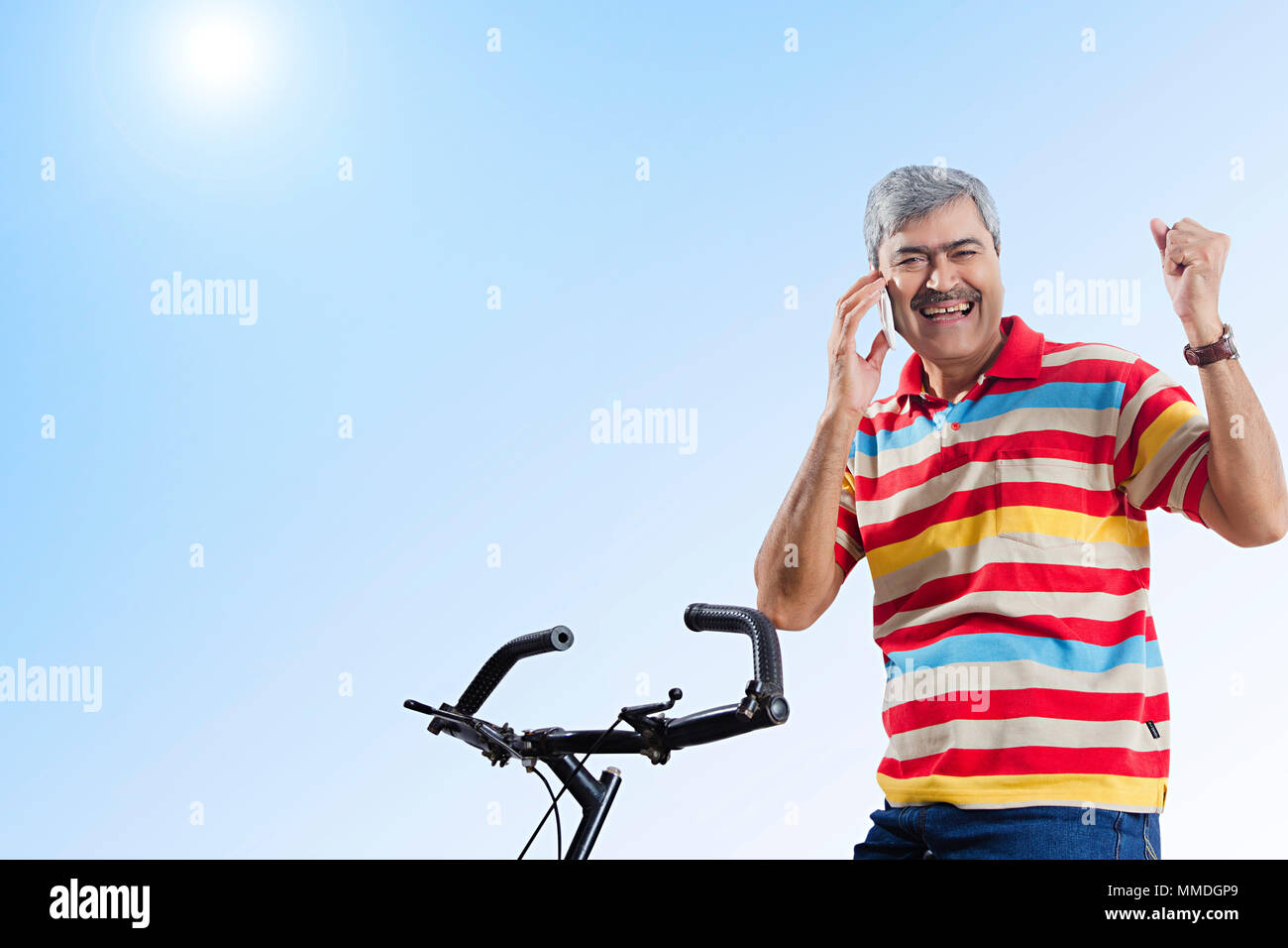 Un Senior uomo seduto ciclo e parlare per telefono cellulare e audizione Goodnews. Foto Stock