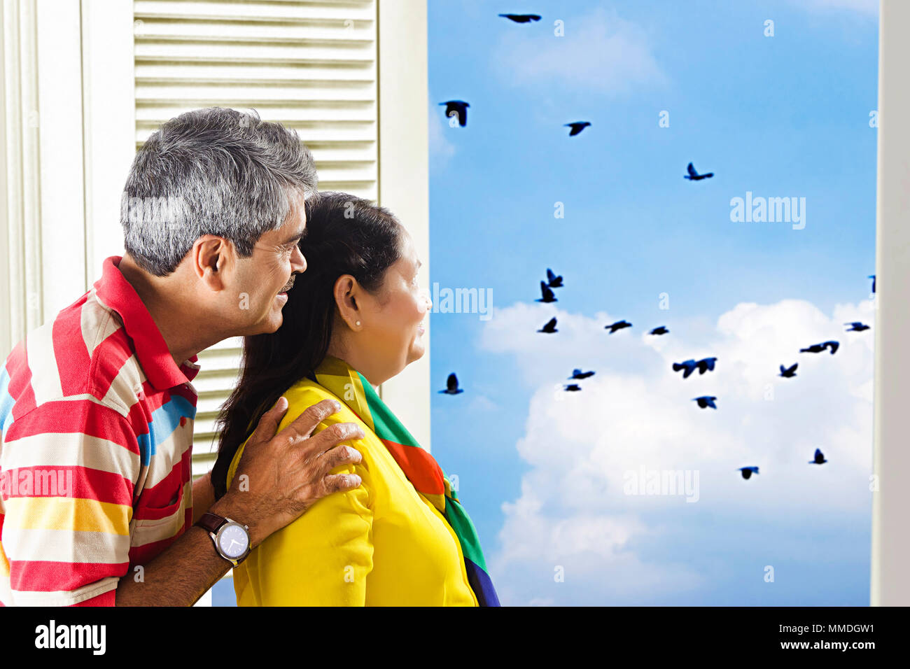 Felice coppia Senior guardando fuori della finestra a guardare gli uccelli a domicilio Foto Stock