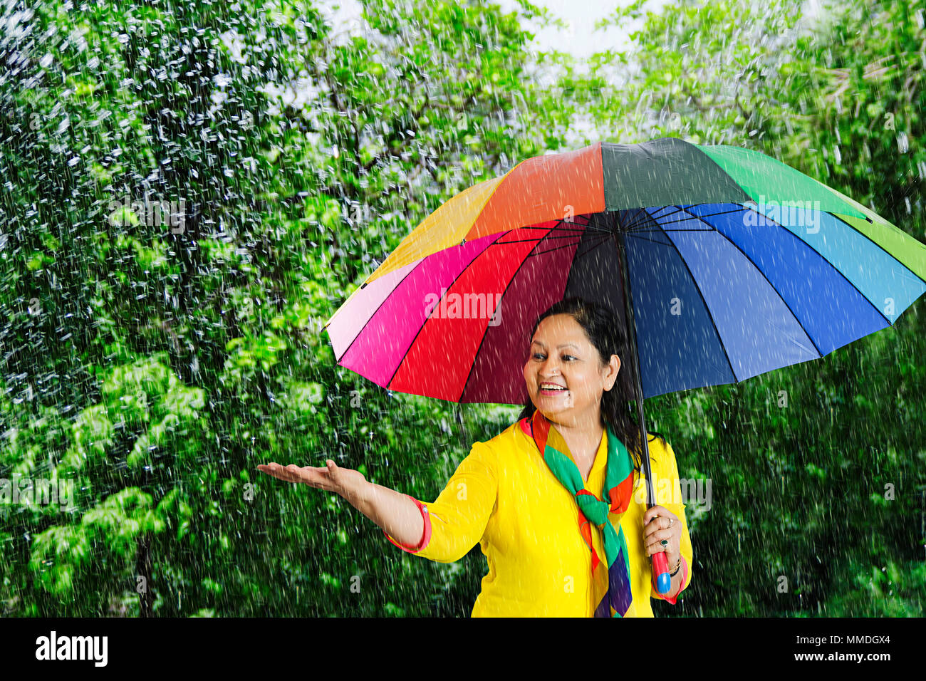 Felice Vecchio donna sotto l ombrello a mettere mano a sentire le gocce di pioggia sul palmare Palm Foto Stock