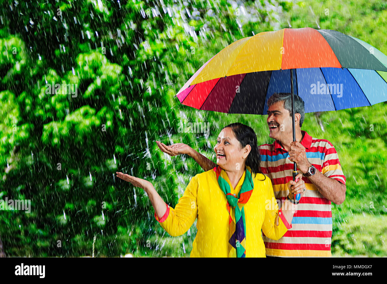 Felice coppia Senior sotto ombrellone mettendo mano a sentire le gocce di pioggia,Palm Foto Stock
