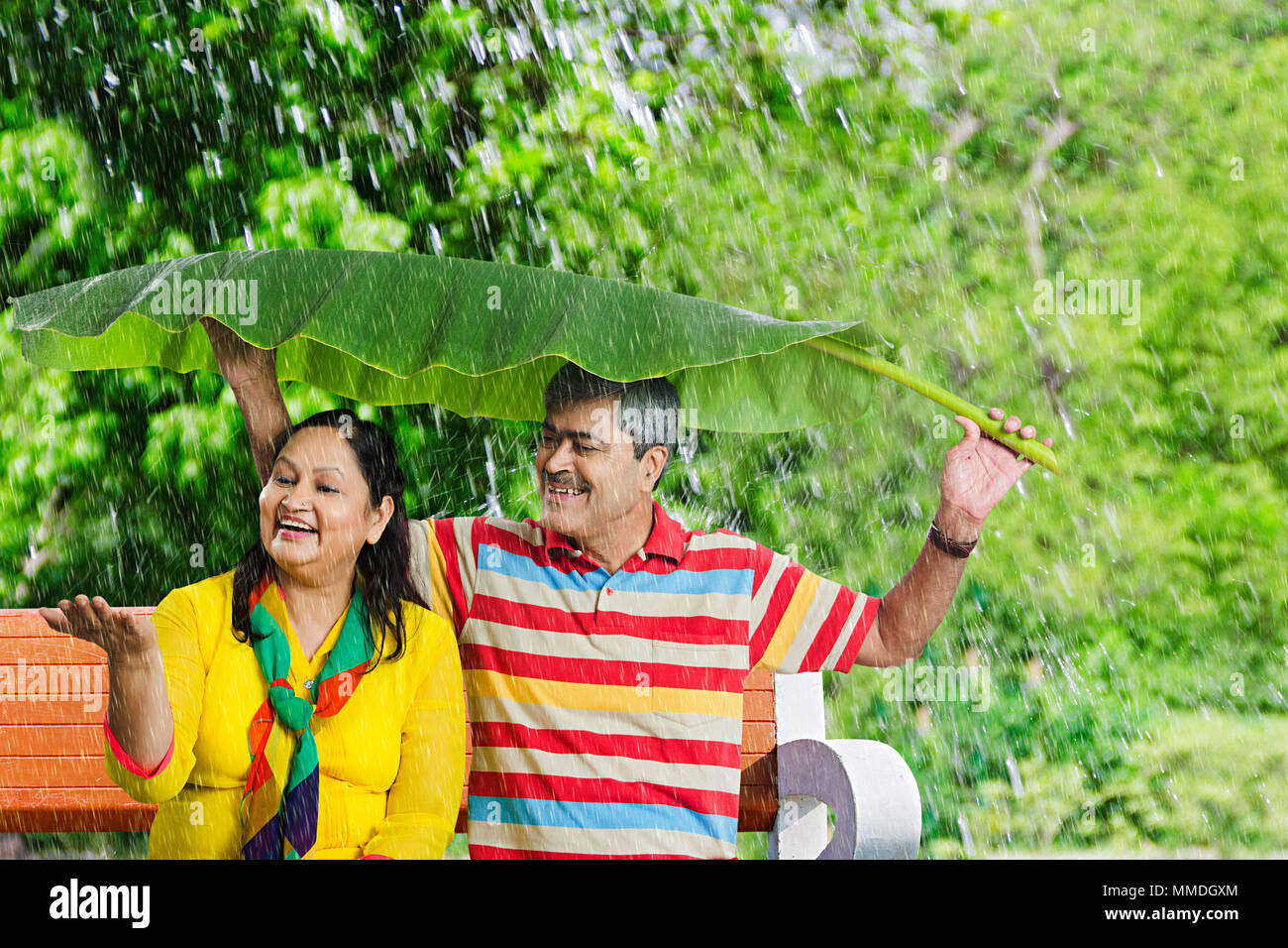 Felice Vecchio giovane seduto sotto Banana-Leaves divertimento Godetevi At-Park Foto Stock