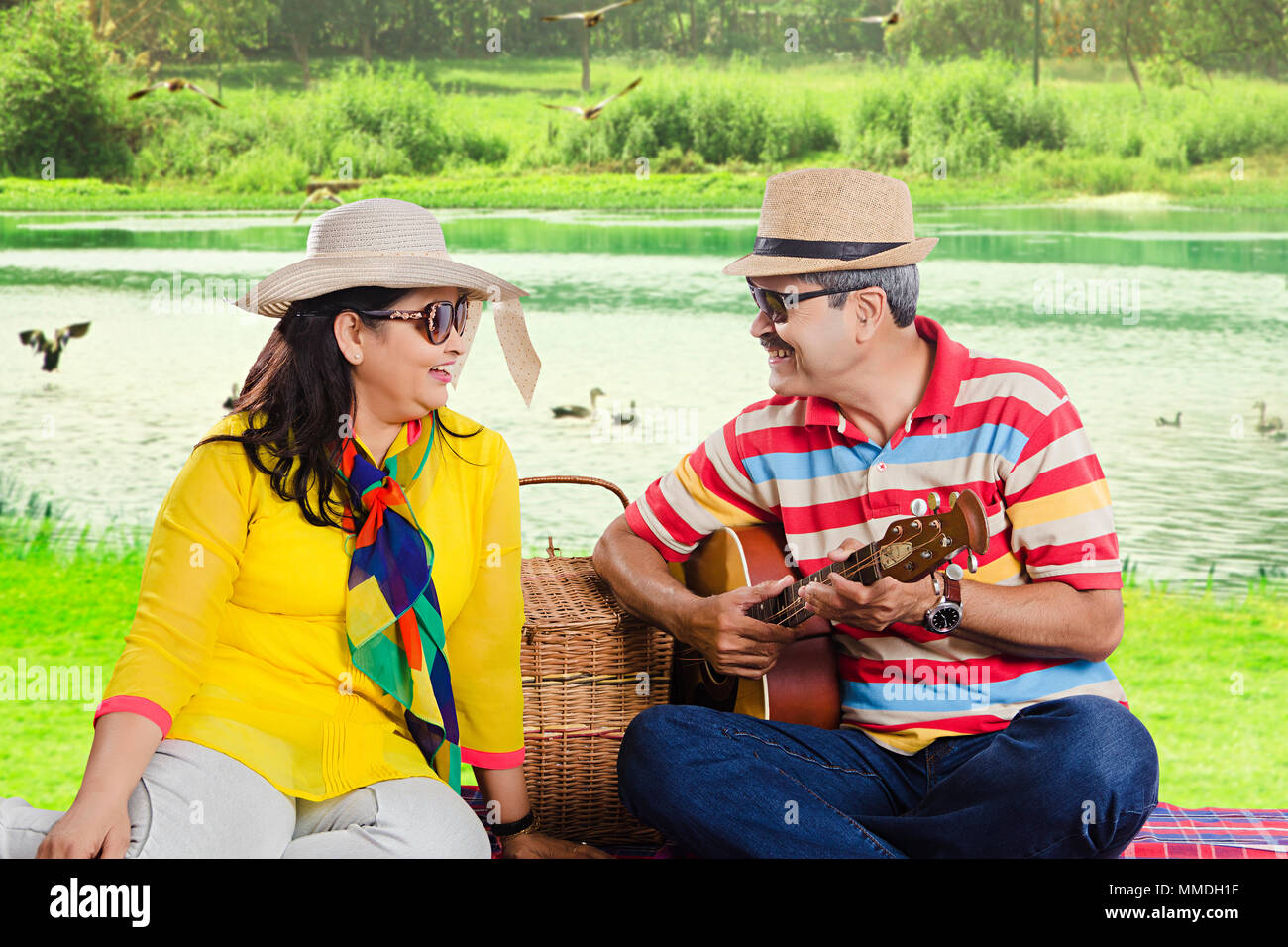 Coppia senior dating divertendosi con la chitarra su Near-Lake picnic Foto Stock