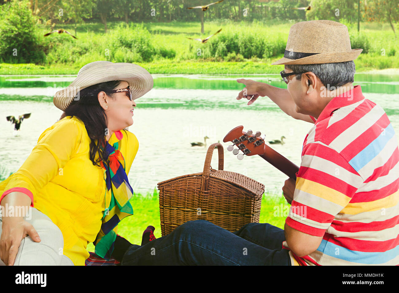 Felice Senior-Couple romantico-data che mostra di puntamento con la chitarra su-Near-Lake picnic Foto Stock