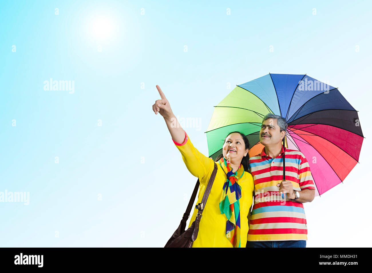 Felice coppia Senior sotto ombrellone insieme puntare il dito che mostra all'aperto Foto Stock