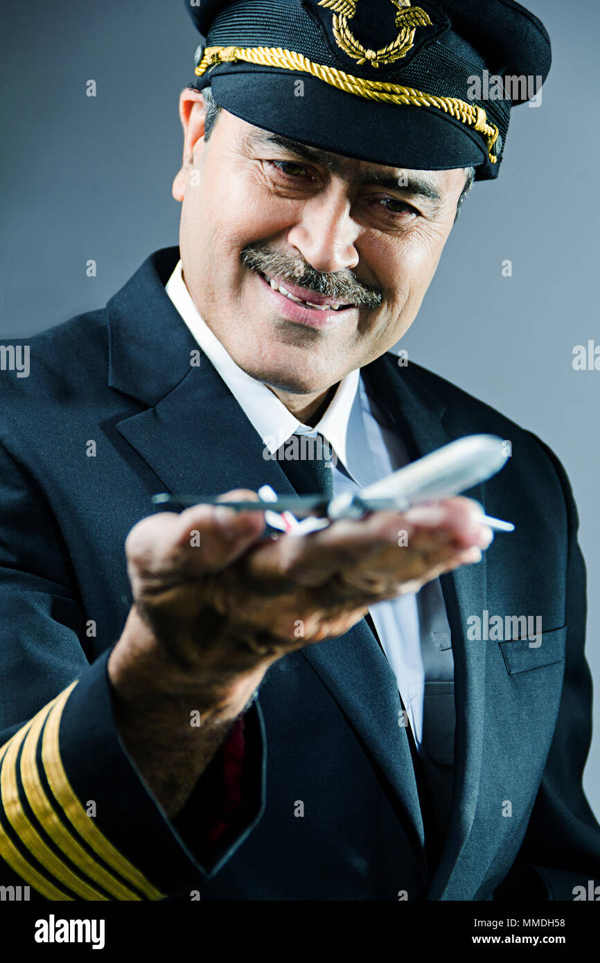 Sorridente maschio Senior pilota con toy Air-Plane sul suo Hand-Palm Foto Stock