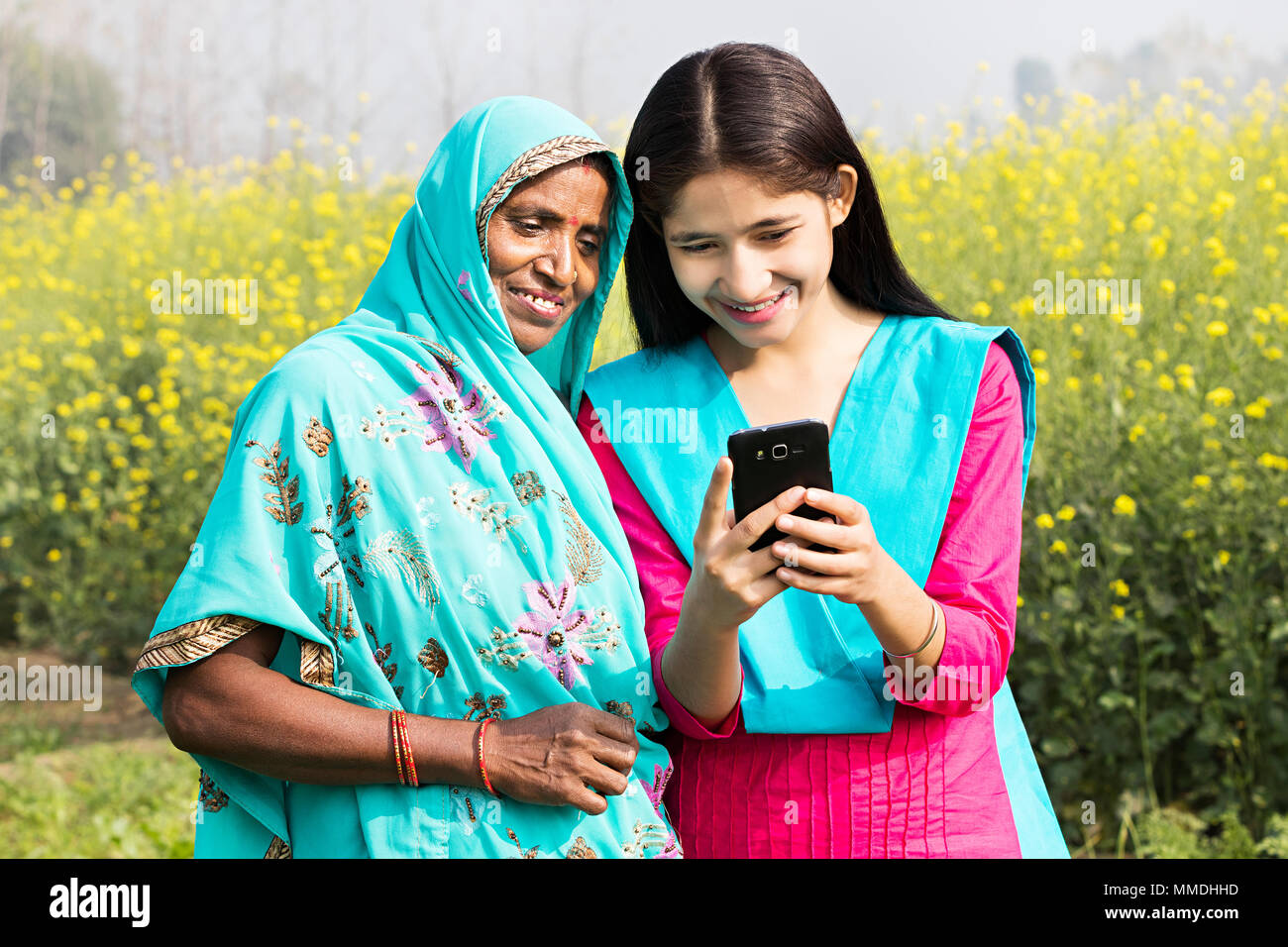 Rural madre e figlia Text-Messaging lettura Cellulare Field-Village Foto Stock