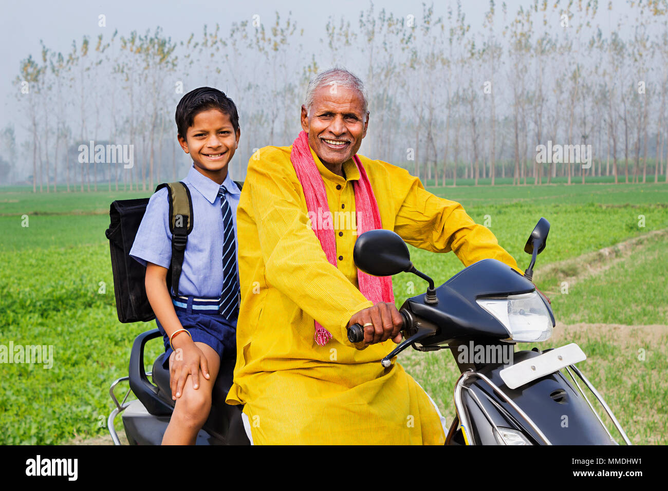 Abitante di villaggio rurale padre e corse School-Boy scooter andando a scuola In-Farm Foto Stock